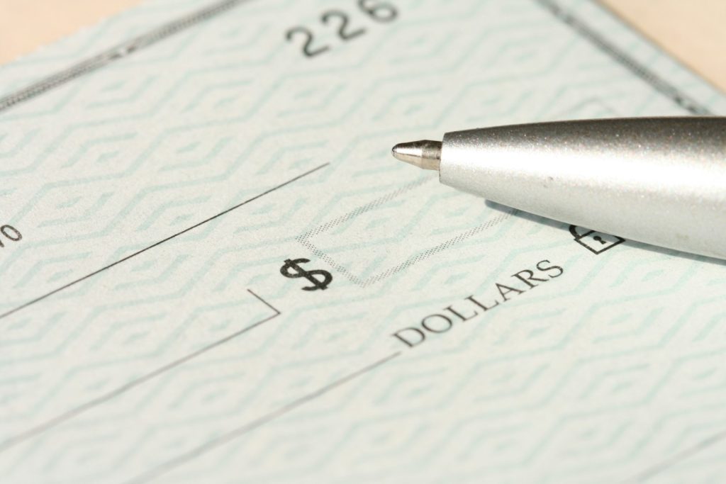 A pen resting on a paycheck beside the dollars line