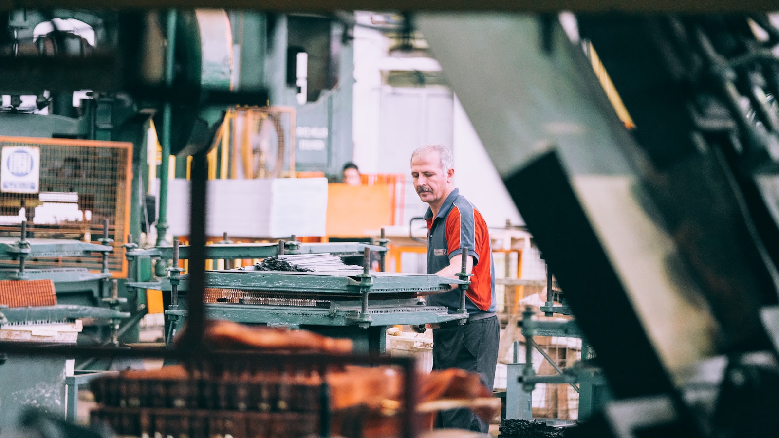 A man in a grey and red shirt operating industrial machinery in a factory