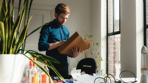 A man standing in an office holding a box